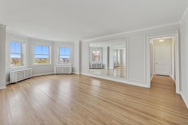 unfurnished room featuring crown molding, radiator heating unit, and light hardwood / wood-style flooring