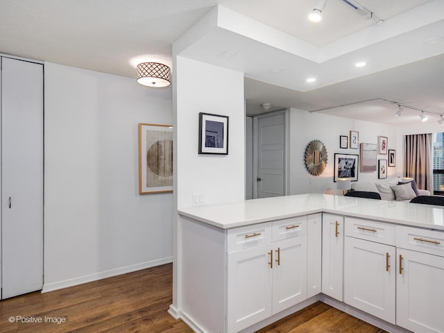 kitchen featuring track lighting, white cabinets, dark hardwood / wood-style floors, and kitchen peninsula