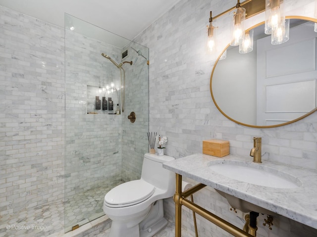 bathroom with toilet, tile walls, sink, and a tile shower