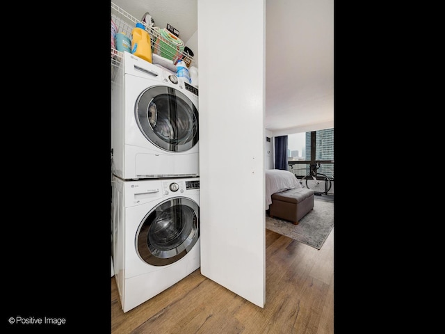 laundry room featuring stacked washer / dryer and hardwood / wood-style flooring