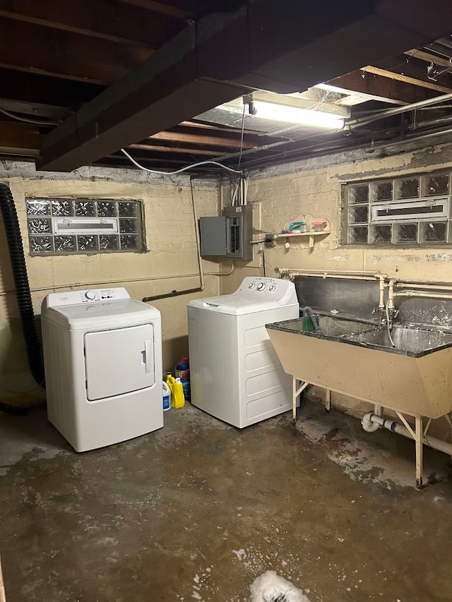 basement featuring electric panel, washer and clothes dryer, and sink