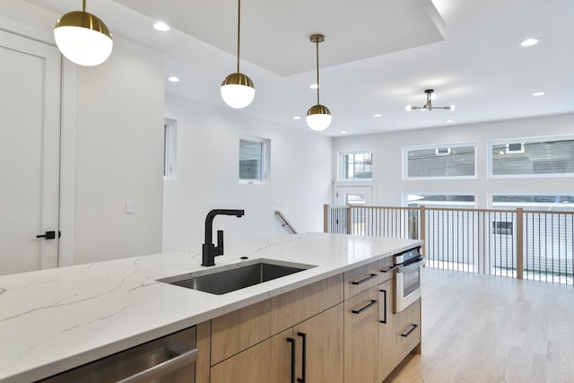 kitchen with light stone countertops, sink, decorative light fixtures, and appliances with stainless steel finishes