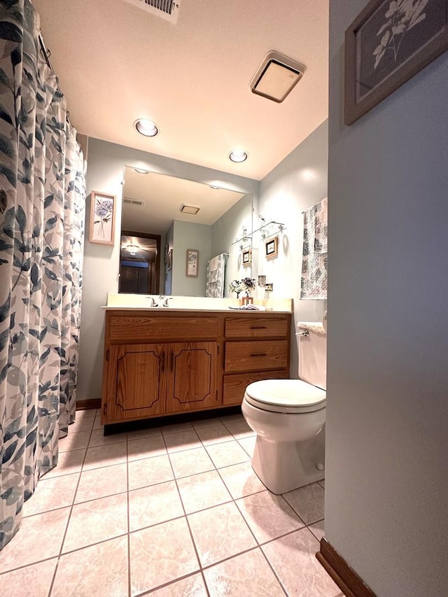 bathroom with toilet, vanity, and tile patterned flooring