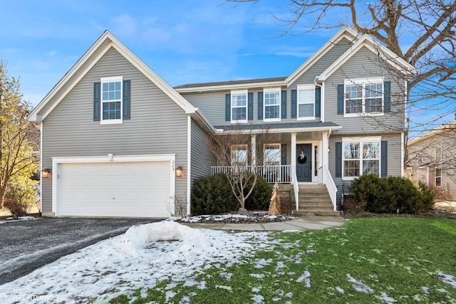 view of property with a garage, covered porch, and a lawn