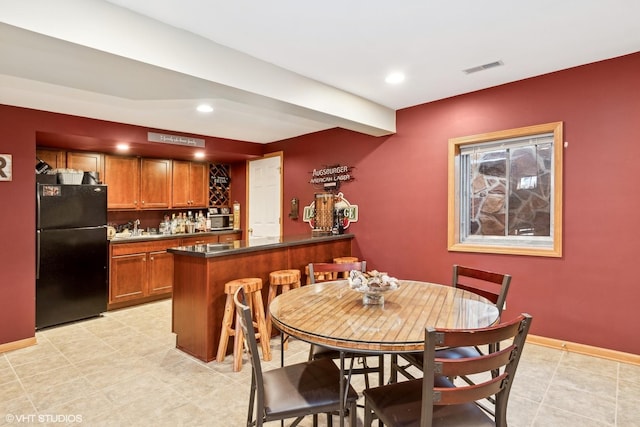 dining space with beamed ceiling and indoor wet bar