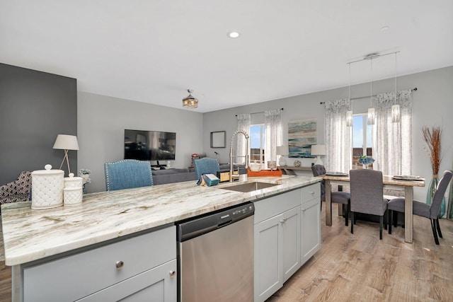 kitchen with white cabinetry, dishwasher, sink, a kitchen island with sink, and light stone counters