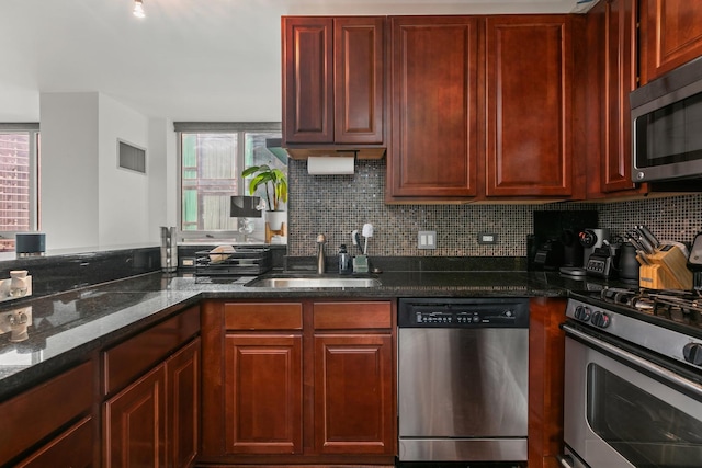 kitchen featuring sink, backsplash, stainless steel appliances, and dark stone counters