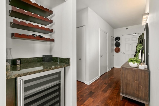 bar featuring beverage cooler, dark hardwood / wood-style flooring, and dark stone countertops