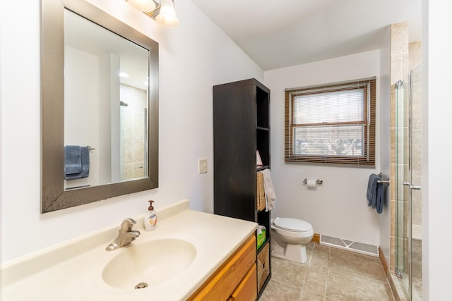 bathroom featuring tile patterned floors, vanity, toilet, and a shower with door