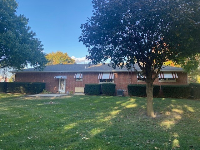 back of house with cooling unit and a lawn