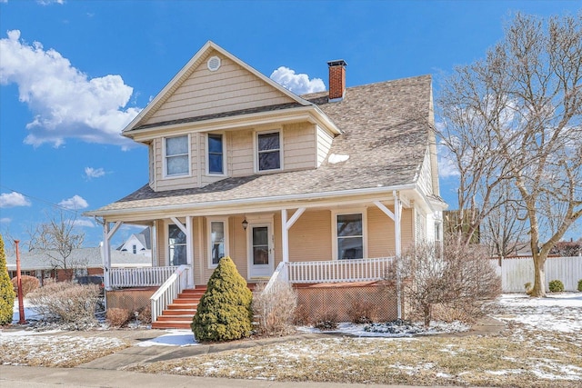 view of front of house featuring covered porch, a shingled roof, and a chimney