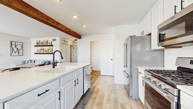 kitchen featuring sink, white cabinetry, light hardwood / wood-style flooring, stainless steel appliances, and beam ceiling