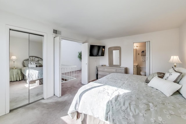 carpeted bedroom with ensuite bathroom and a closet