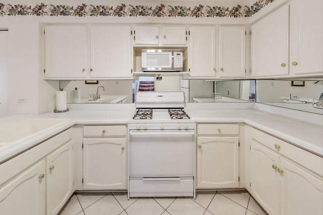 kitchen featuring white cabinetry, sink, light tile patterned floors, and white appliances