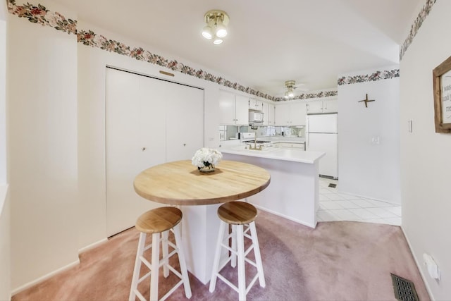 kitchen with ceiling fan, light colored carpet, white cabinets, and white appliances