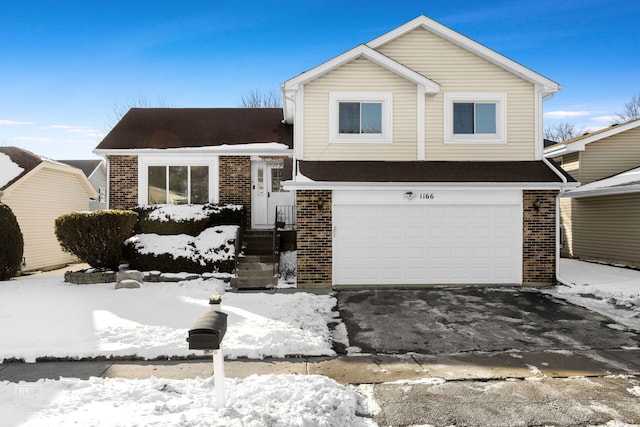 tri-level home featuring a garage, brick siding, and driveway