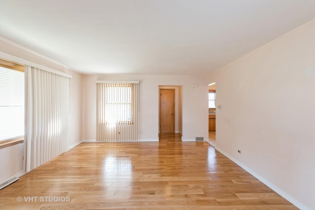 spare room featuring light wood-type flooring and baseboards