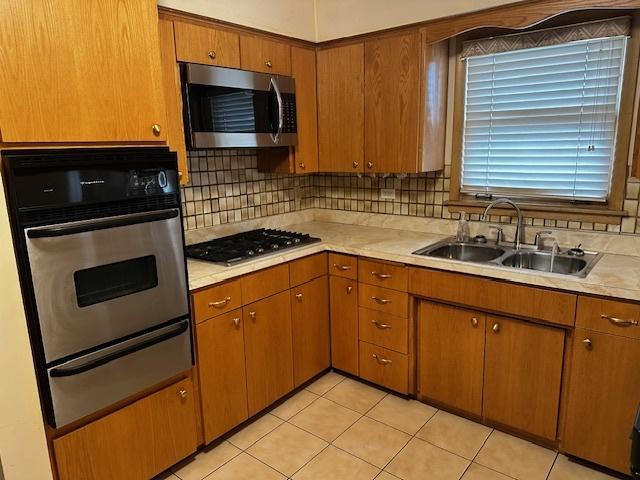 kitchen with light tile patterned floors, appliances with stainless steel finishes, sink, and backsplash