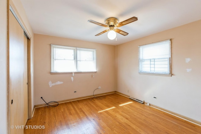 unfurnished bedroom featuring light wood-type flooring, a closet, multiple windows, and baseboards