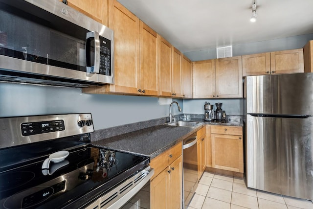 kitchen with rail lighting, appliances with stainless steel finishes, light tile patterned flooring, light brown cabinetry, and sink