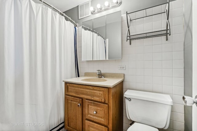 bathroom featuring tile walls, toilet, and vanity