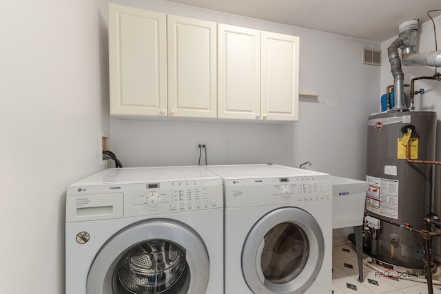 clothes washing area featuring light tile patterned floors, cabinets, washer and clothes dryer, and gas water heater