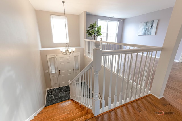 stairs featuring an inviting chandelier and hardwood / wood-style flooring