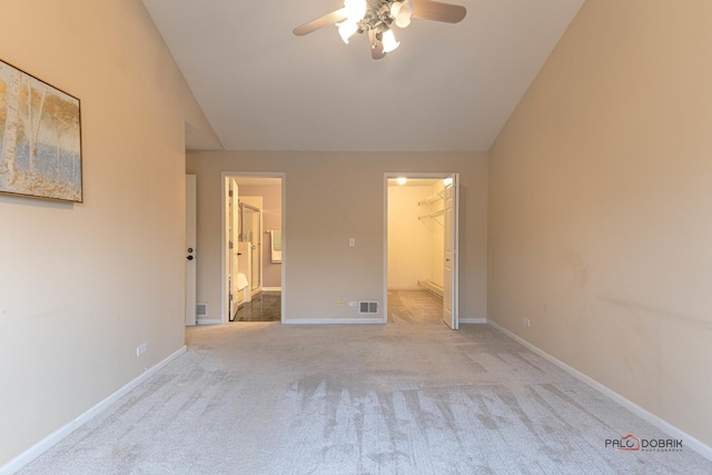 unfurnished bedroom with ceiling fan, a closet, lofted ceiling, light colored carpet, and a walk in closet