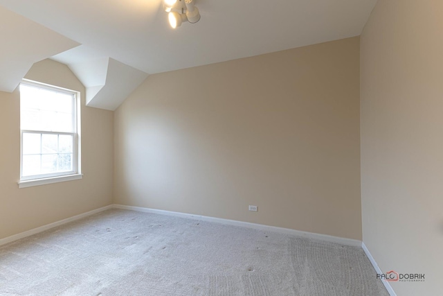 bonus room with light colored carpet and vaulted ceiling