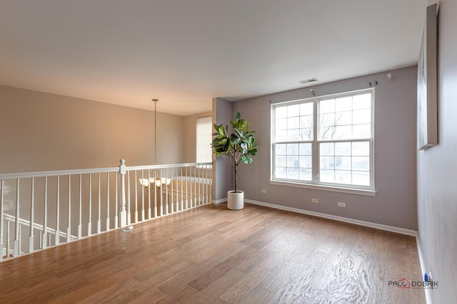 empty room featuring wood-type flooring and a chandelier