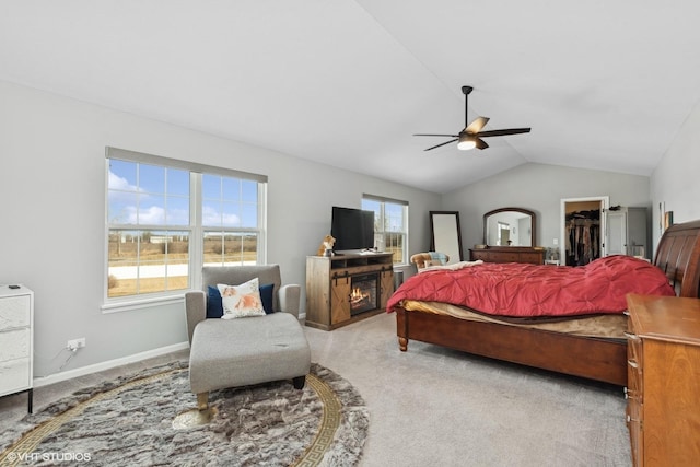 bedroom featuring ceiling fan, a walk in closet, vaulted ceiling, and light carpet