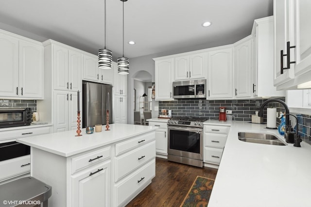 kitchen featuring appliances with stainless steel finishes, sink, pendant lighting, and white cabinets