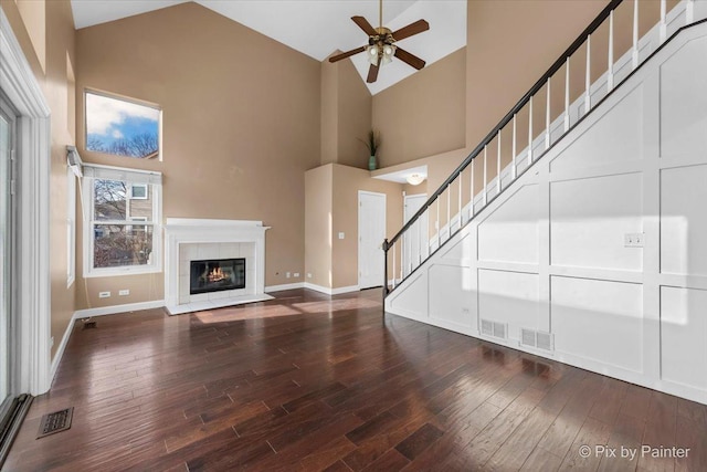 unfurnished living room featuring ceiling fan, hardwood / wood-style floors, a tile fireplace, and high vaulted ceiling