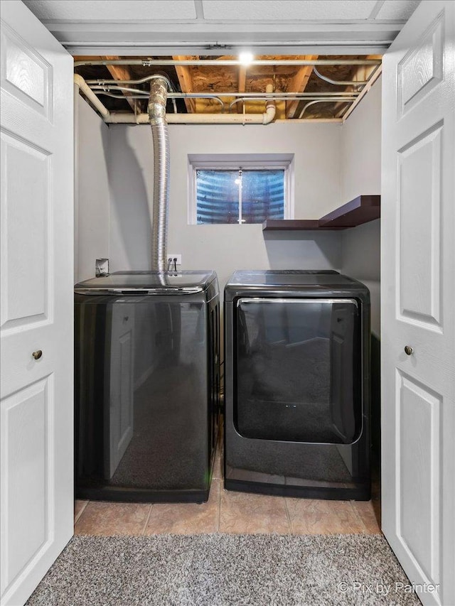 clothes washing area featuring light tile patterned floors and washing machine and dryer