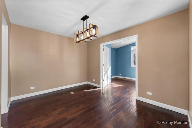 empty room featuring dark hardwood / wood-style flooring and a notable chandelier