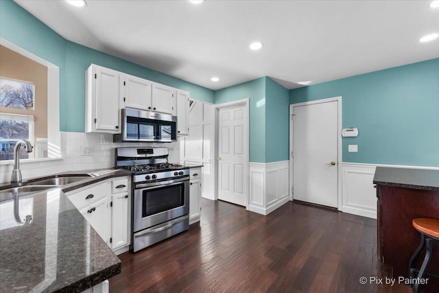 kitchen with white cabinets, dark wood-type flooring, stainless steel appliances, decorative backsplash, and sink