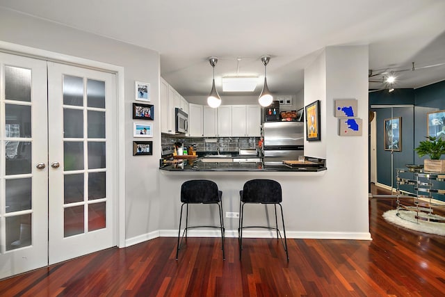 kitchen featuring white cabinetry, a breakfast bar area, kitchen peninsula, stainless steel appliances, and french doors