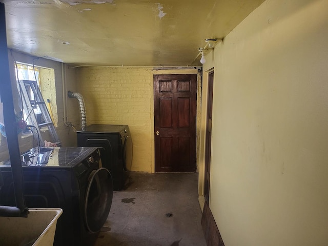 laundry room featuring brick wall, a wood stove, and washing machine and clothes dryer