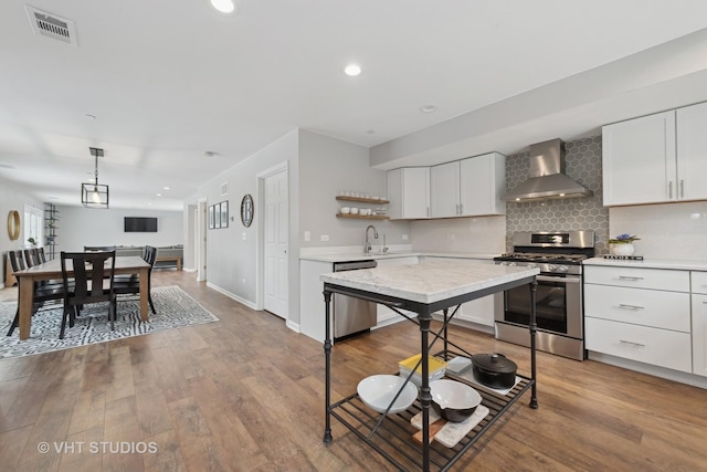 kitchen with backsplash, white cabinetry, appliances with stainless steel finishes, and wall chimney exhaust hood