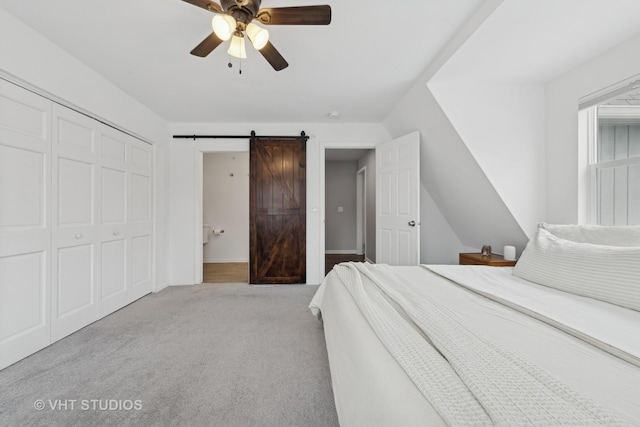 unfurnished bedroom with a closet, ceiling fan, a barn door, and light colored carpet