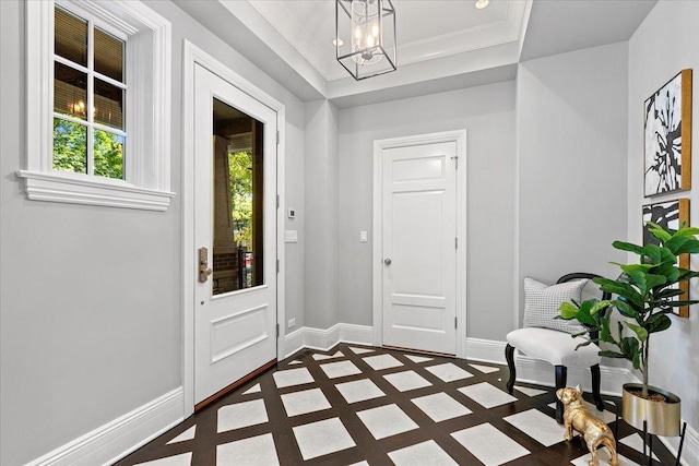 foyer with crown molding and a notable chandelier