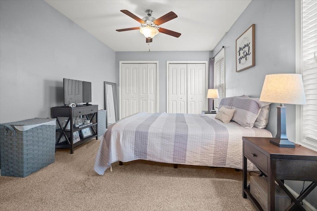 bedroom with carpet flooring, two closets, and ceiling fan