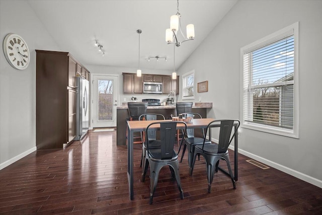 dining room with vaulted ceiling, dark hardwood / wood-style floors, and a notable chandelier