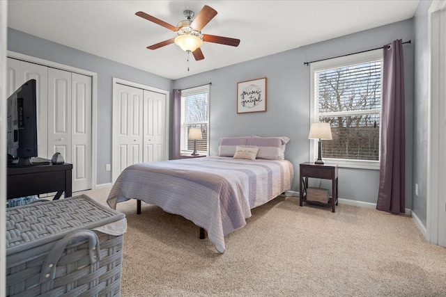 carpeted bedroom featuring multiple windows, two closets, and ceiling fan