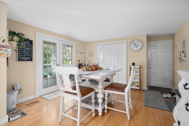 dining area with light wood-type flooring and french doors