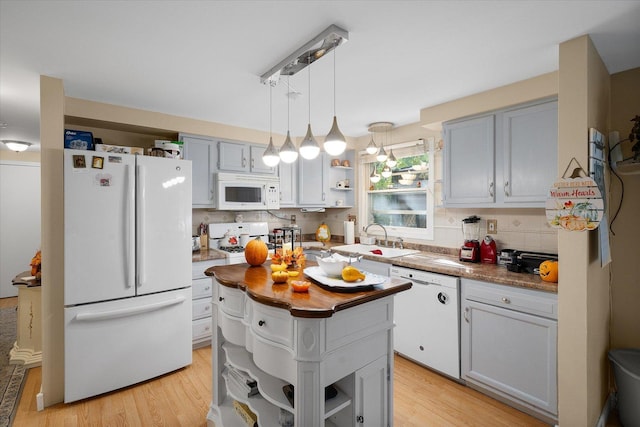 kitchen featuring sink, white appliances, backsplash, light hardwood / wood-style floors, and decorative light fixtures