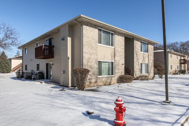 snow covered rear of property featuring a balcony