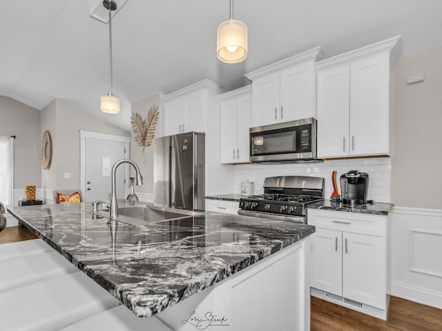 kitchen featuring lofted ceiling, appliances with stainless steel finishes, pendant lighting, and dark stone counters