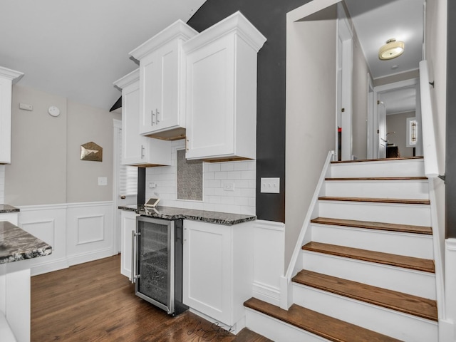 kitchen with white cabinets, beverage cooler, dark wood-type flooring, dark stone counters, and tasteful backsplash