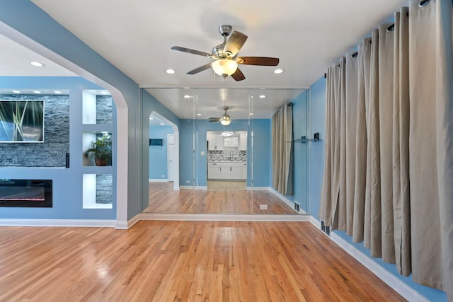 unfurnished living room with ceiling fan, a fireplace, and light hardwood / wood-style floors